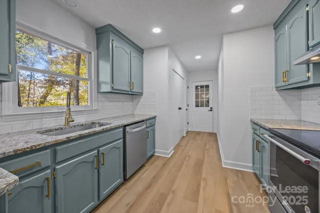 a kitchen with granite countertop cabinets stainless steel appliances a sink and a large window
