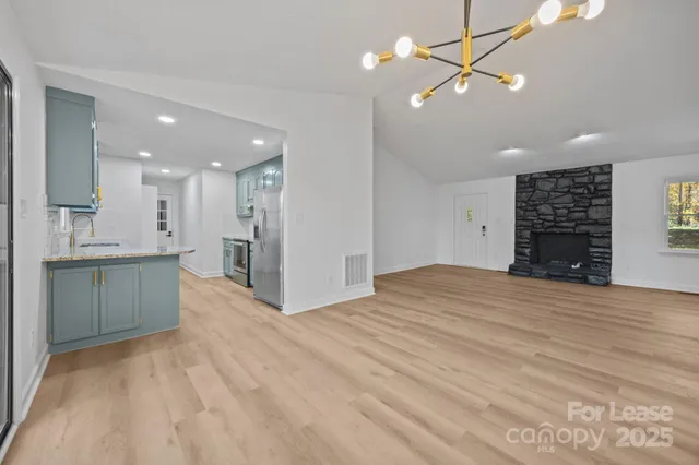 a view of kitchen and empty room with wooden floor