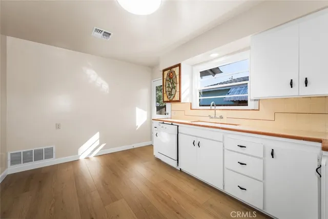a hallway with white cabinets and wooden floor