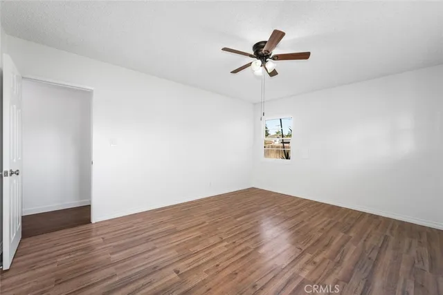 a view of empty room with wooden floor and ceiling fan