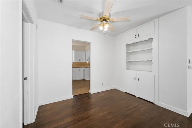 an empty room with wooden floor closet and windows