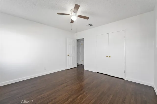 an empty room with wooden floor and ceiling fan