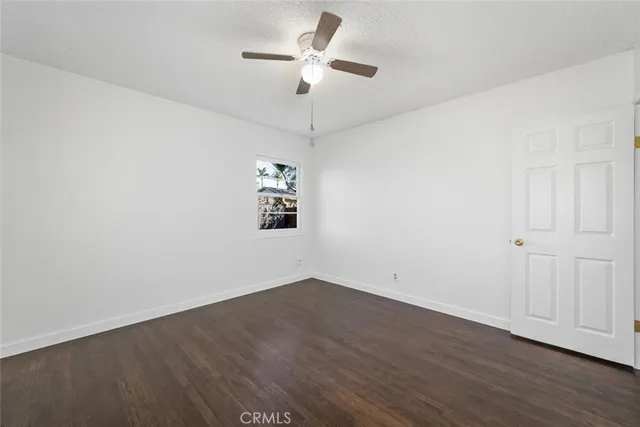a view of a room with wooden floor and a ceiling fan