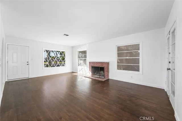 an empty room with wooden floor a fireplace and windows