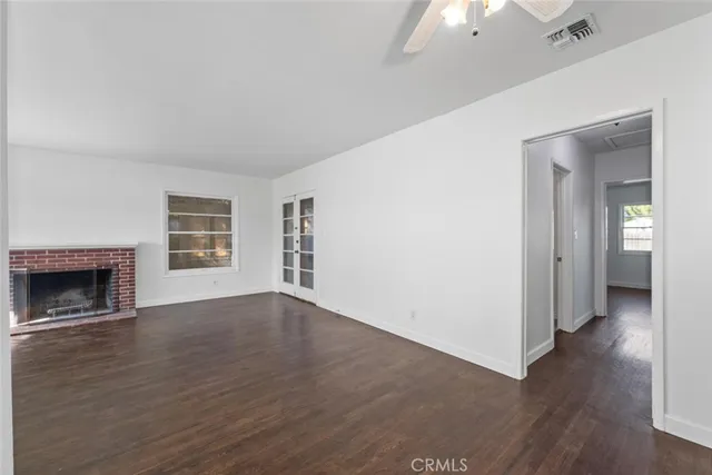 an empty room with wooden floor fireplace and windows