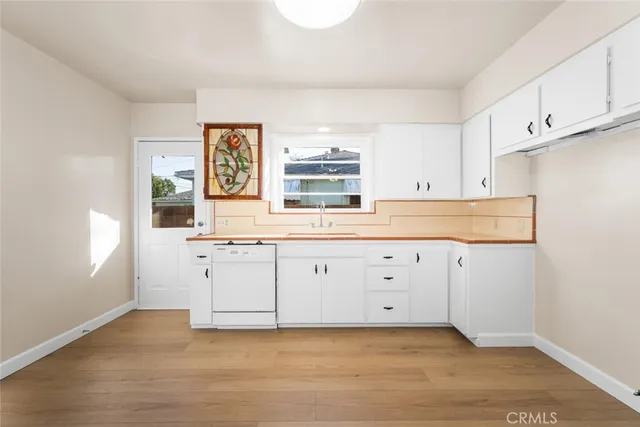 a kitchen with white cabinets and window