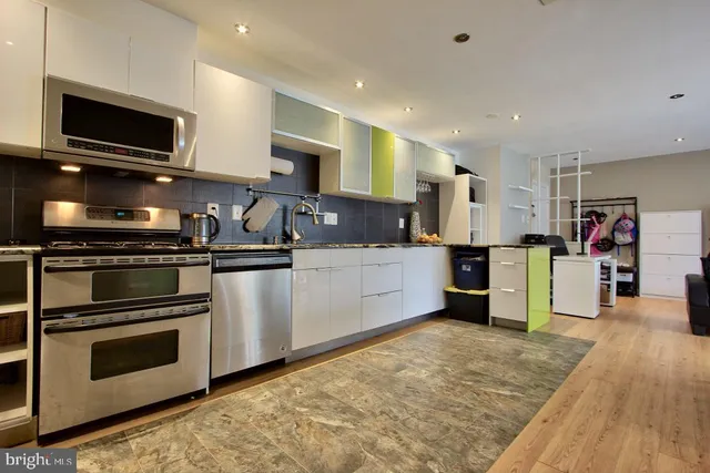 a kitchen with stainless steel appliances a sink a stove a refrigerator a sink a counter top space and cabinets