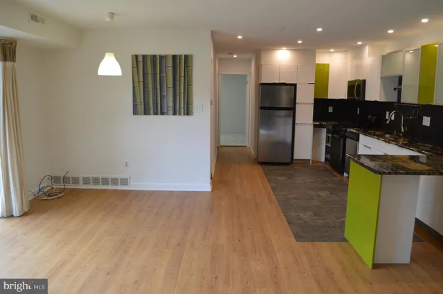 a kitchen with granite countertop a refrigerator a stove a microwave oven with white cabinets and wooden floor