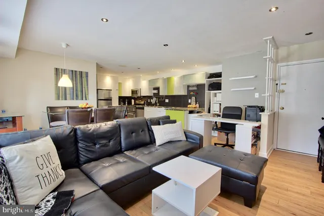 a living room with furniture a flat screen tv and kitchen view