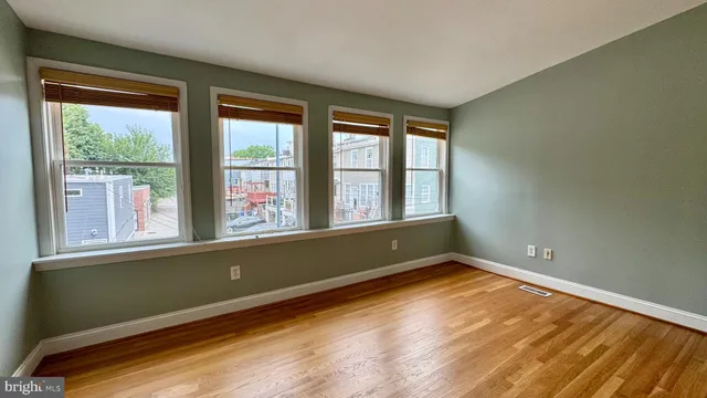 an empty room with wooden floor and windows