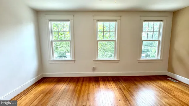 an empty room with wooden floor and windows