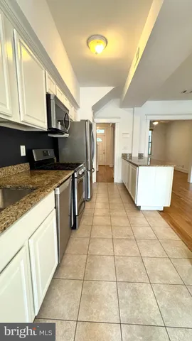 a large white kitchen with stainless steel appliances granite countertop a stove a sink a microwave and a refrigerator