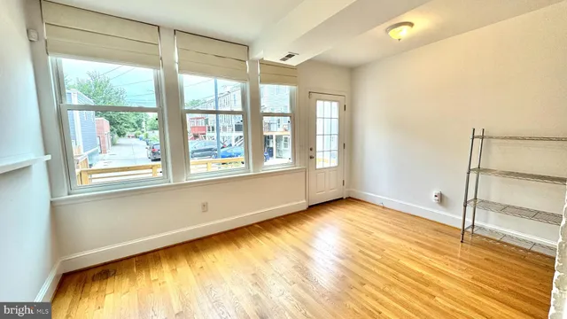 a view of an empty room with a window and wooden floor