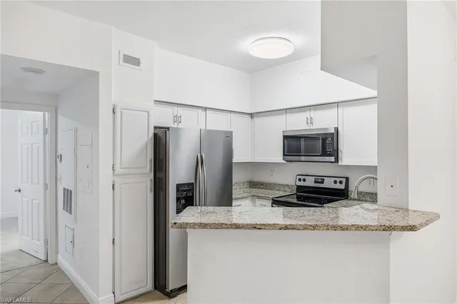 a kitchen with stainless steel appliances granite countertop a refrigerator a stove a sink and white cabinets