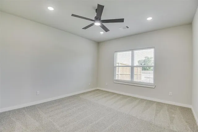 an empty room with a ceiling fan and window
