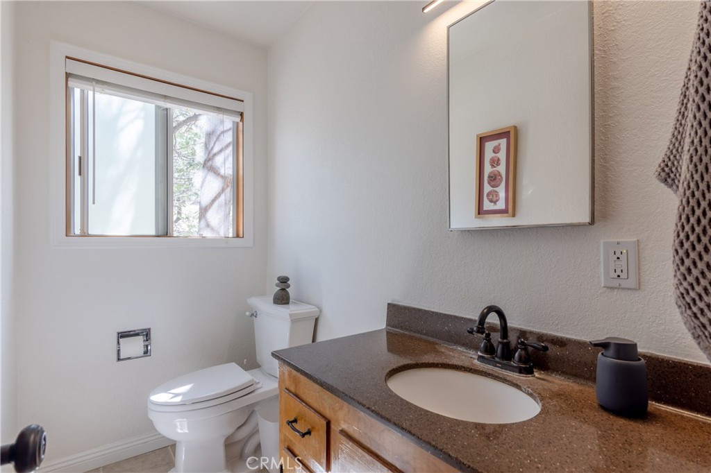 26704 Raven Road Wrightwood, CA 92397 - Photo 17 of 19 a bathroom with a granite countertop sink toilet and a mirror