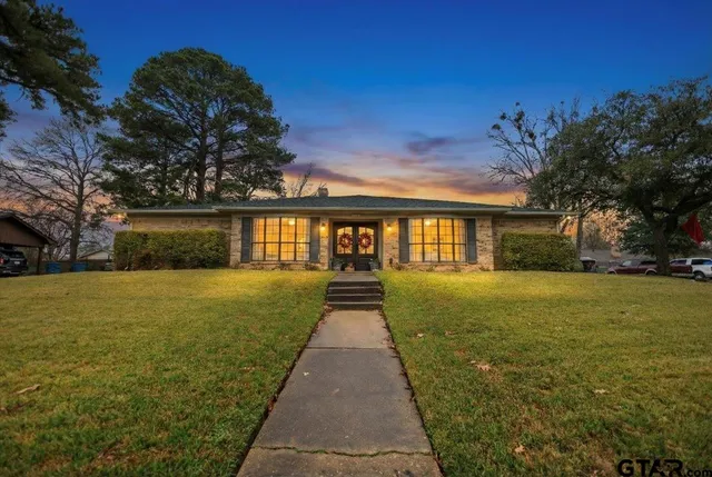 a view of a brick house next to a yard with big trees