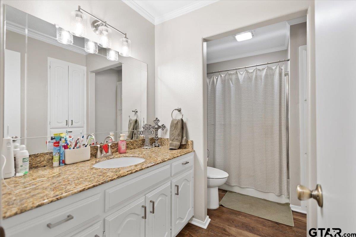 1606 Timothy Street Henderson, TX 75654 - Photo 24 of 33 a bathroom with double vanity sinks a toilet a mirror and shower