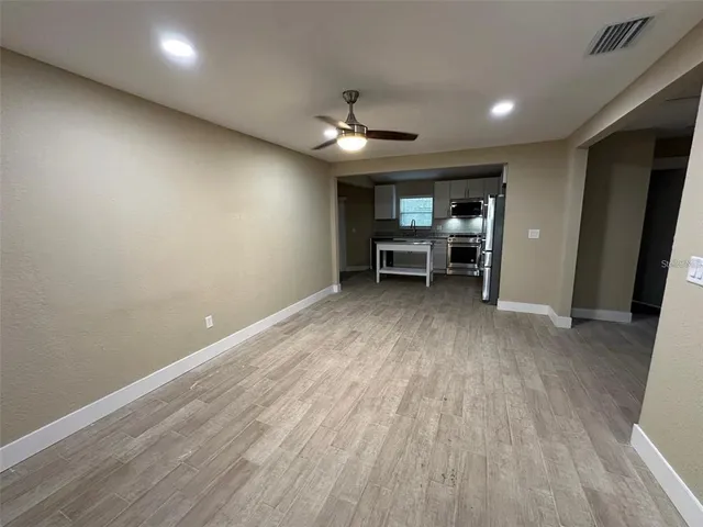 an empty room with wooden floor and a ceiling fan