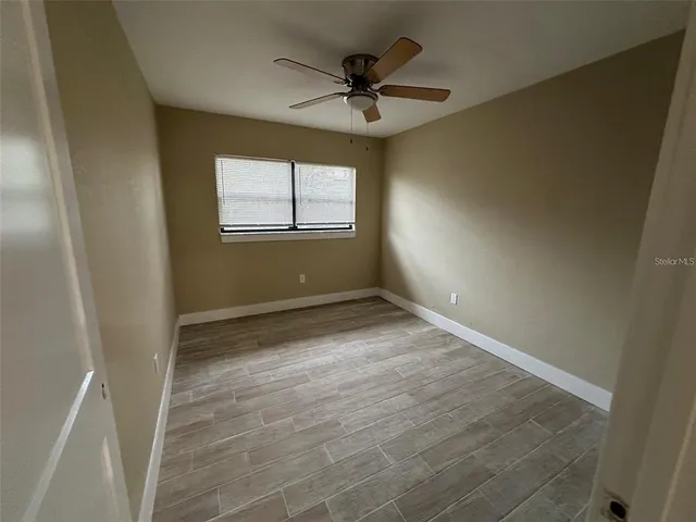 an empty room with windows and ceiling fan
