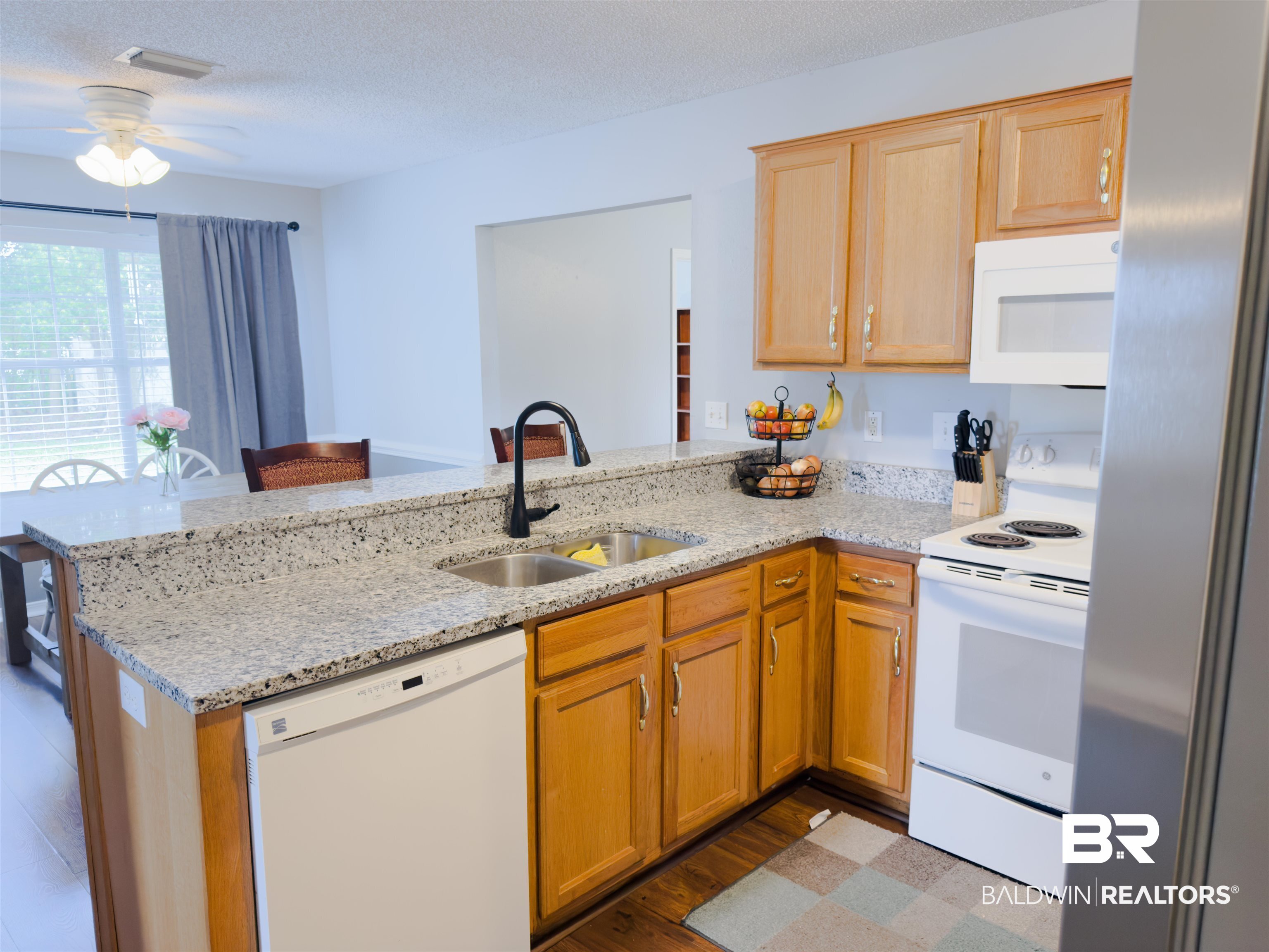 129 Pennbrooke Loop Foley, AL 36535 - Photo 22 of 44 Kitchen featuring white appliances, a peninsula, light stone counters, a ceiling fan, and light wood-style floors