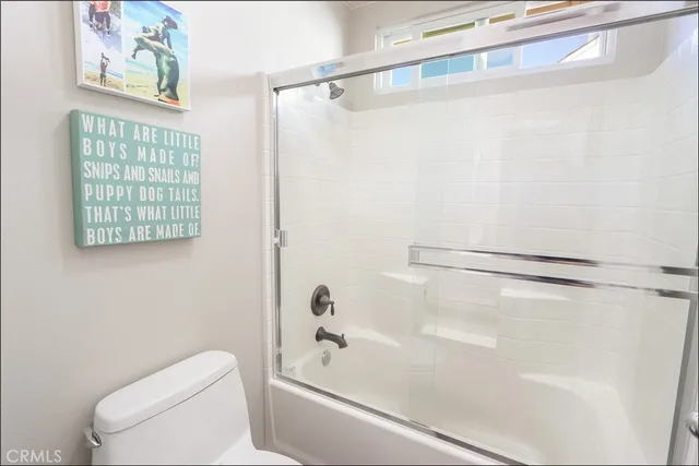 a bathroom with a shower a toilet and a window