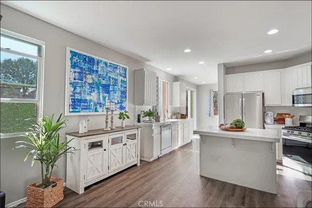 a kitchen with stainless steel appliances a white refrigerator a kitchen island a stove a sink cabinets and wooden floor