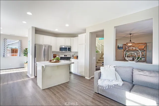 a living room with stainless steel appliances furniture and a kitchen view