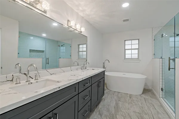 a bathroom with a double vanity sink a mirror and a bathtub