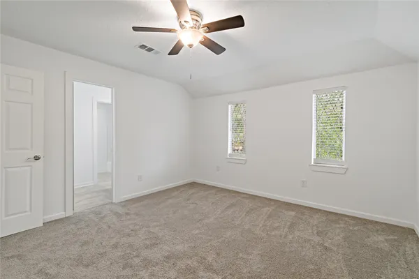 an empty room with windows and fan