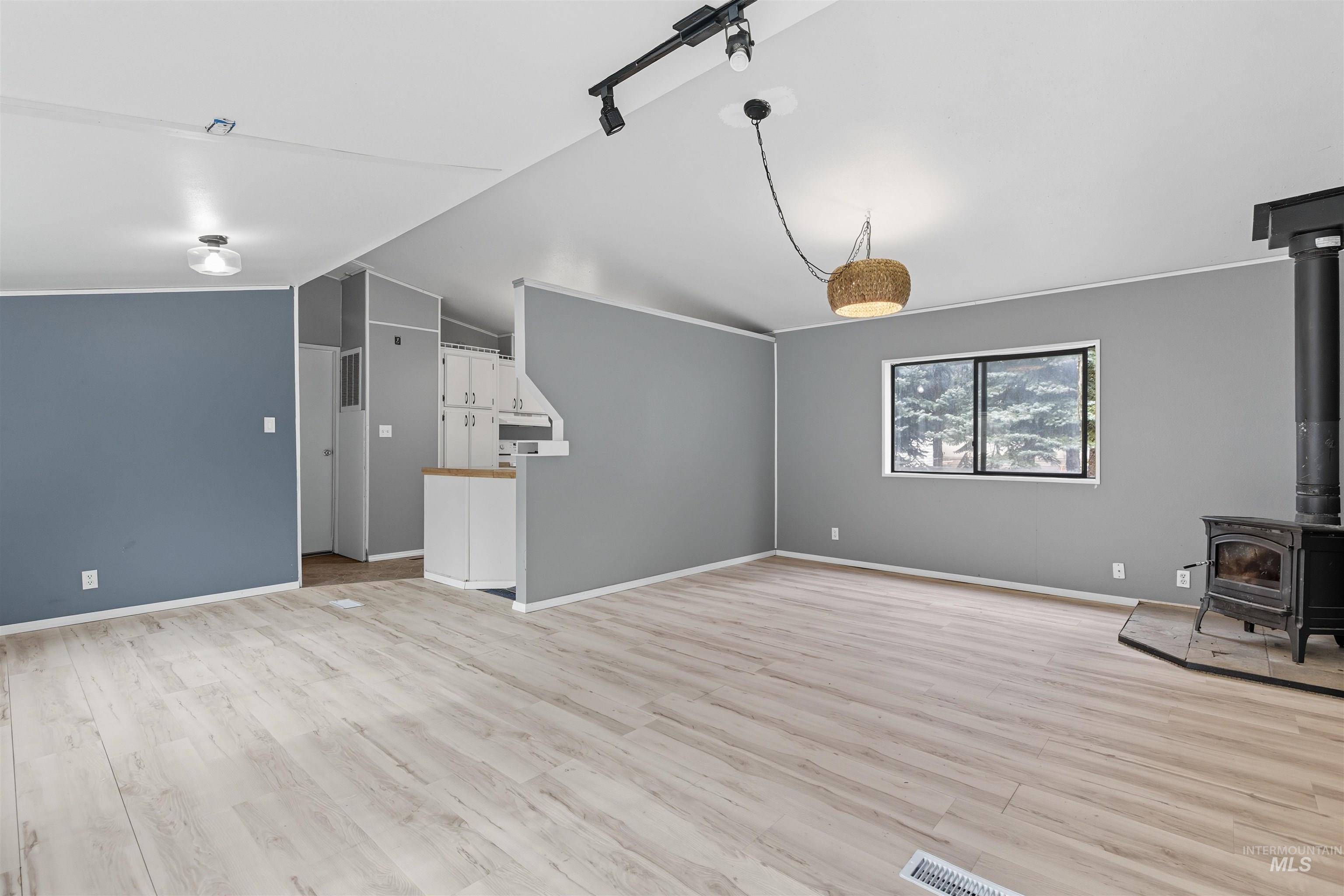 609 North Almon Street, Unit 2003 Moscow, ID 83843 - Photo 8 of 18 Unfurnished living room featuring a wood stove, light wood finished floors, and lofted ceiling