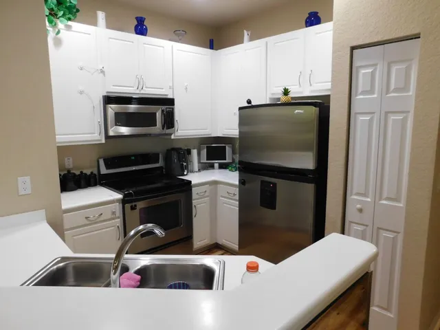 a kitchen with stainless steel appliances a sink a stove a microwave a refrigerator and cabinets