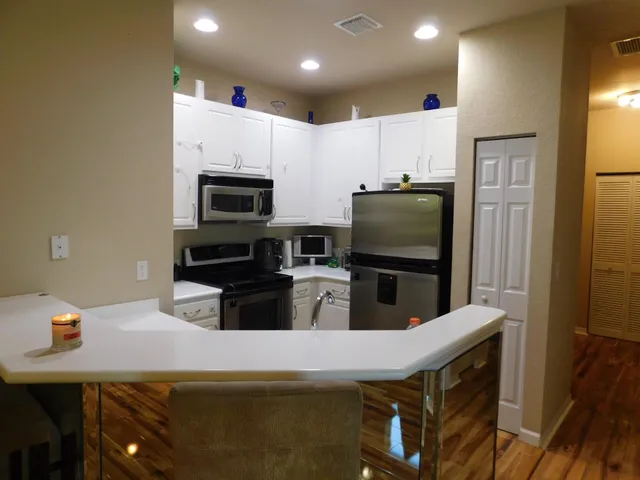 a kitchen with stainless steel appliances a stove a microwave a sink a refrigerator and white cabinets
