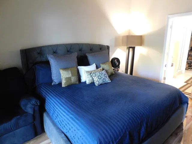 a large bed sitting in a bedroom next to a window and lamp