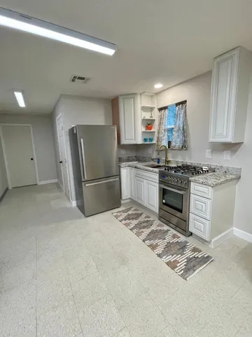 a kitchen with stainless steel appliances granite countertop a refrigerator stove top oven and sink