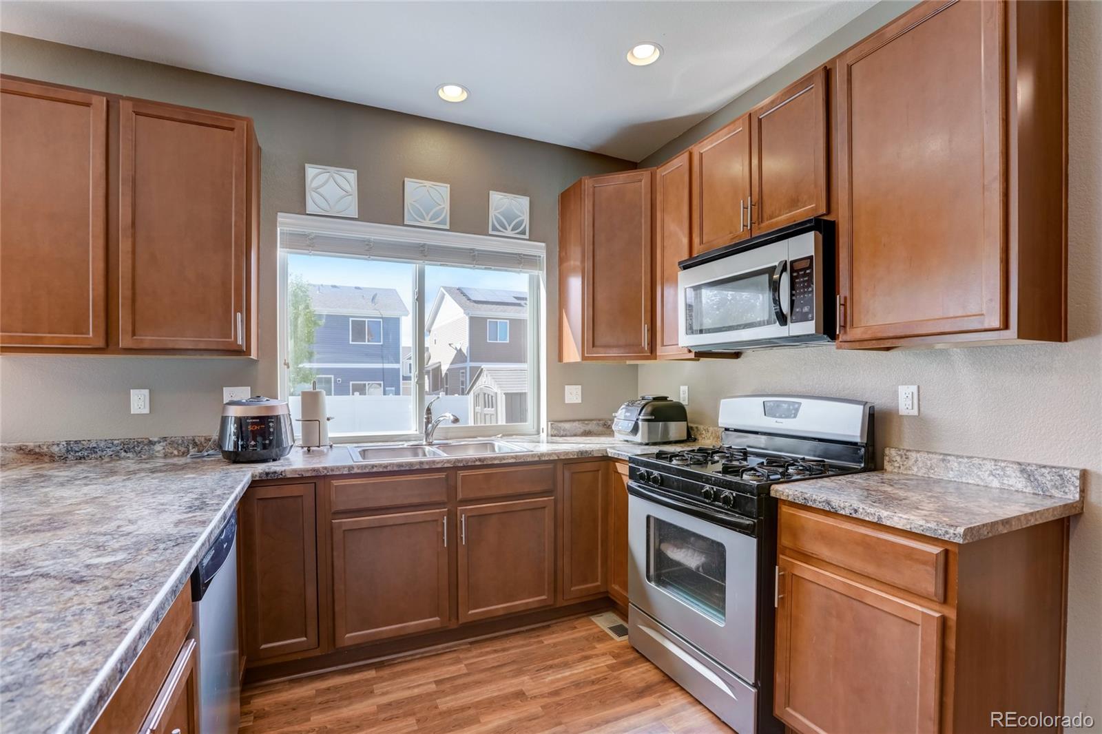 5545 Liverpool Street Denver, CO 80249 - Photo 11 of 40 a kitchen with stainless steel appliances granite countertop a stove a sink and a microwave