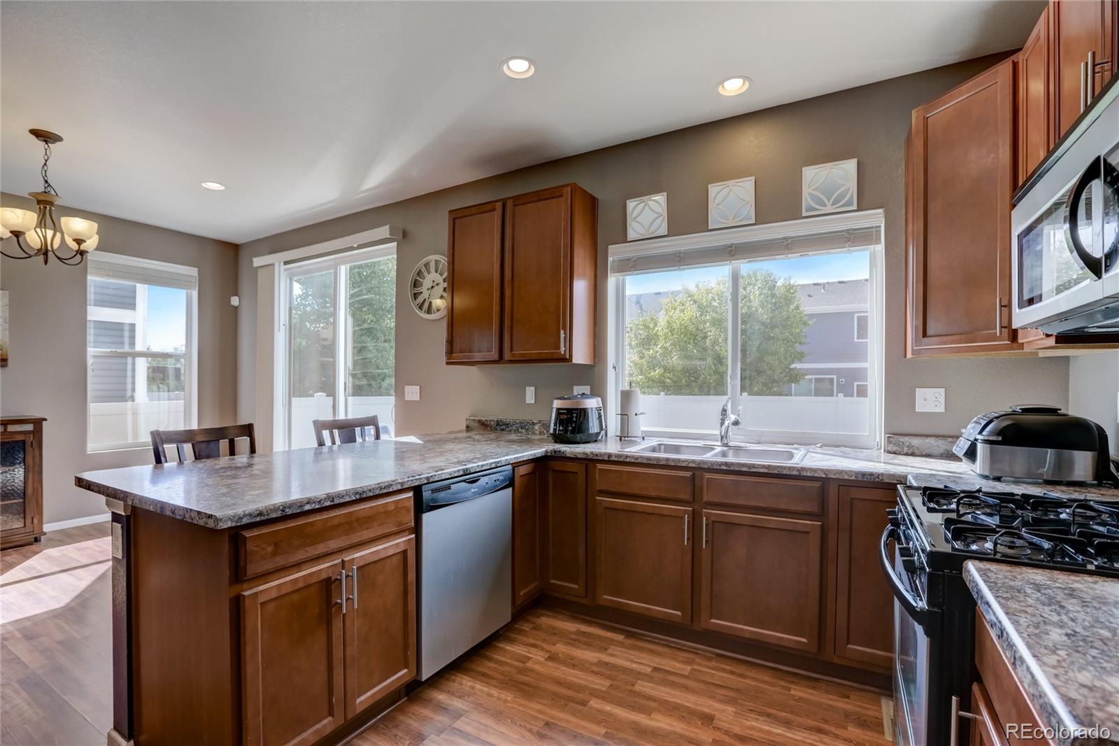 5545 Liverpool Street Denver, CO 80249 - Photo 12 of 40 a kitchen with stainless steel appliances granite countertop a sink stove and cabinets