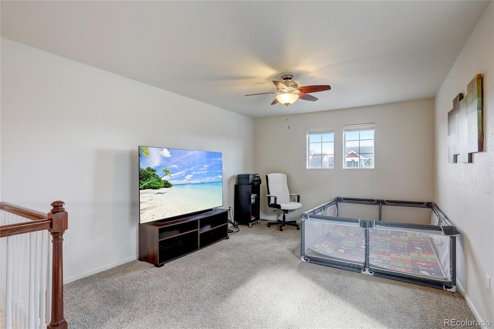 5545 Liverpool Street Denver, CO 80249 - Photo 21 of 40 a living room with furniture a projector and a flat screen tv