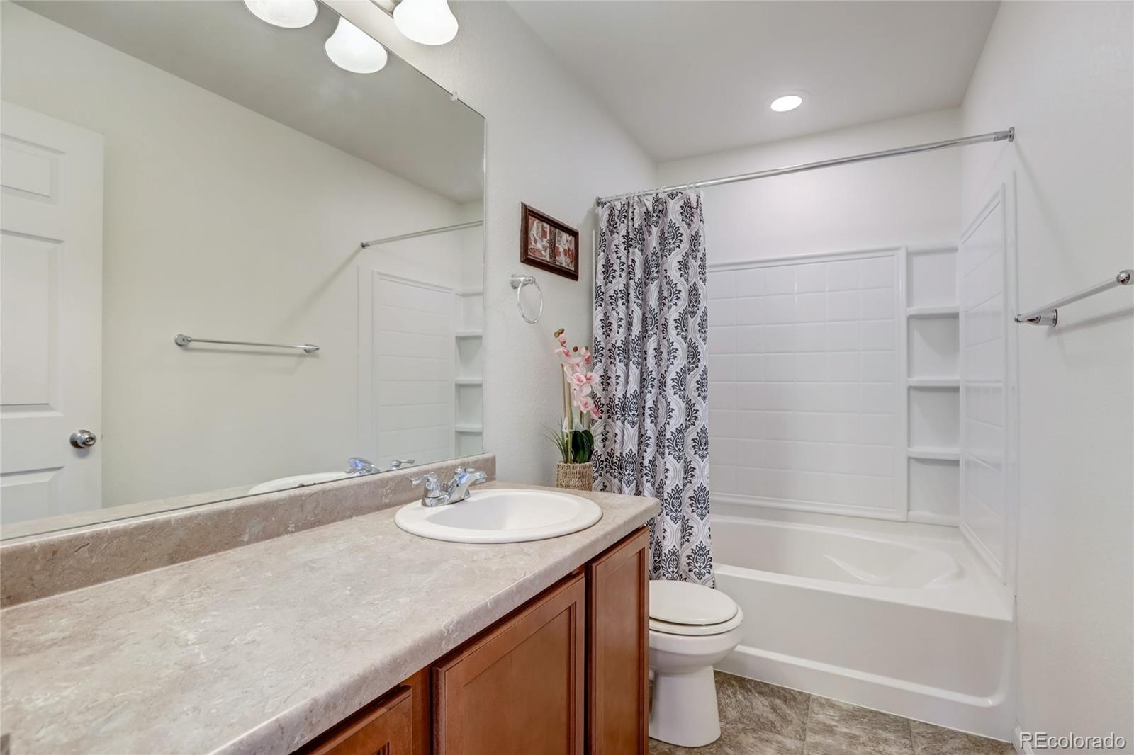 5545 Liverpool Street Denver, CO 80249 - Photo 23 of 40 a bathroom with a granite countertop sink toilet and shower