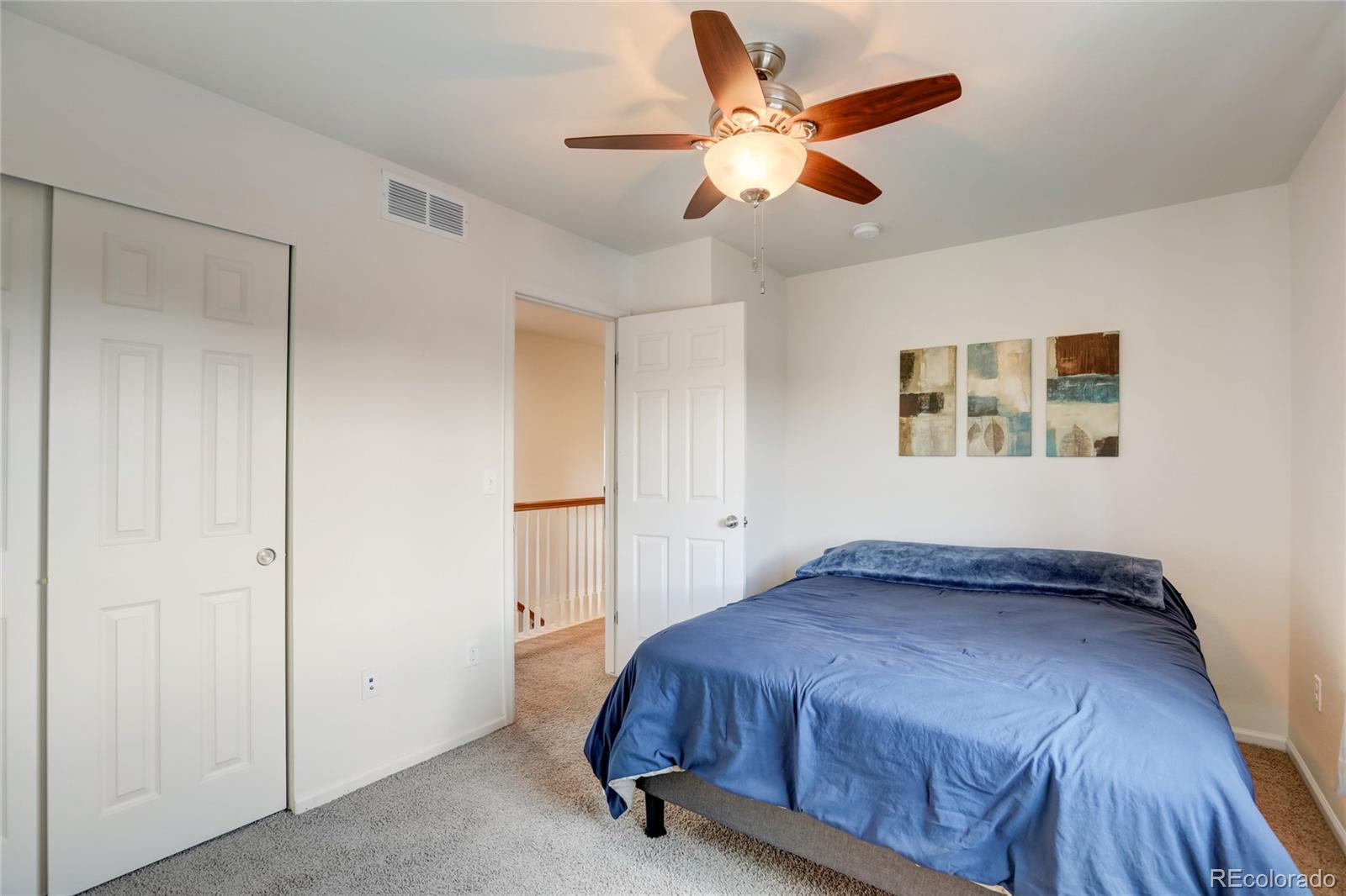 5545 Liverpool Street Denver, CO 80249 - Photo 26 of 40 a bedroom with a large bed and a ceiling fan