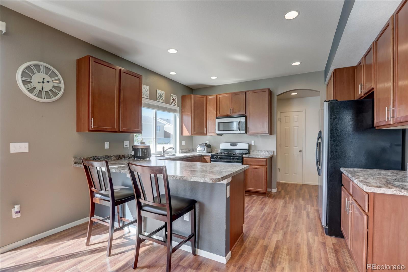 5545 Liverpool Street Denver, CO 80249 - Photo 8 of 40 a kitchen with stainless steel appliances granite countertop a stove top oven a refrigerator a sink and dishwasher with wooden floor