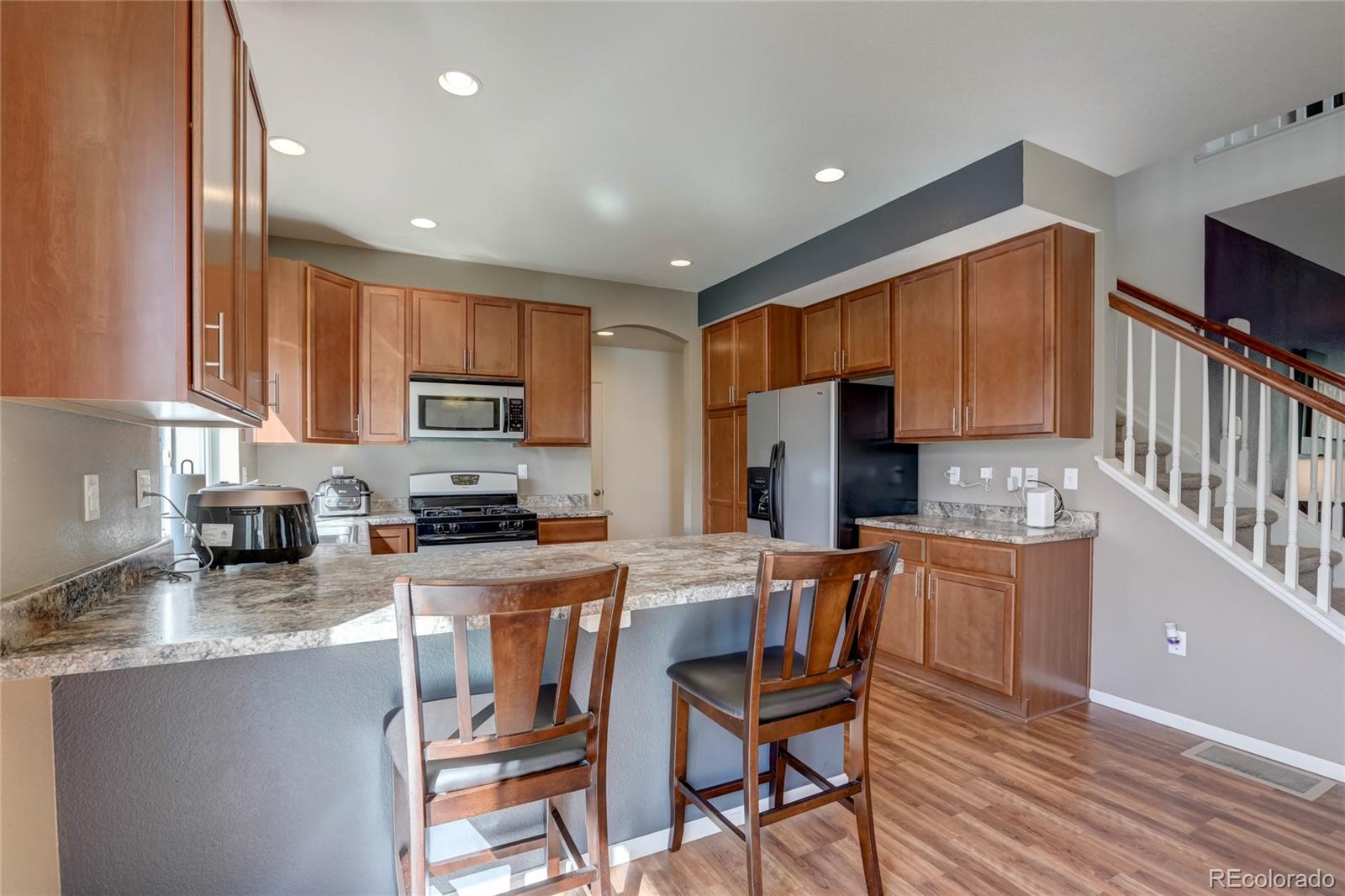5545 Liverpool Street Denver, CO 80249 - Photo 9 of 40 a kitchen with stainless steel appliances granite countertop a stove top oven a sink dishwasher and a refrigerator with wooden floor