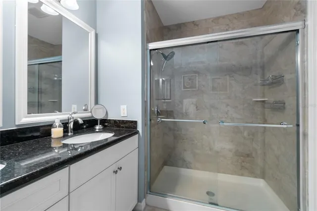 a bathroom with a granite countertop bathtub shower sink vanity and mirror