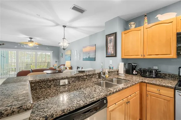 a kitchen with stainless steel appliances granite countertop a sink a stove and a wooden cabinets