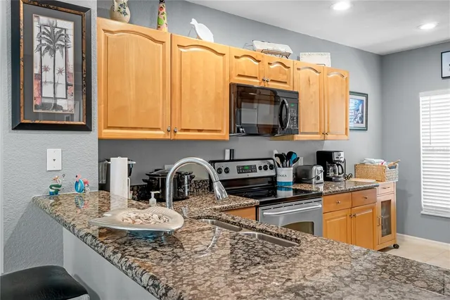 a kitchen with granite countertop a stove a sink and a microwave