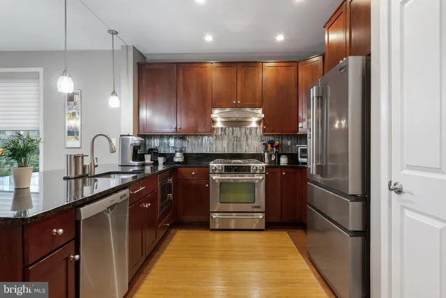 a kitchen with stainless steel appliances granite countertop refrigerator a sink a stove and oven