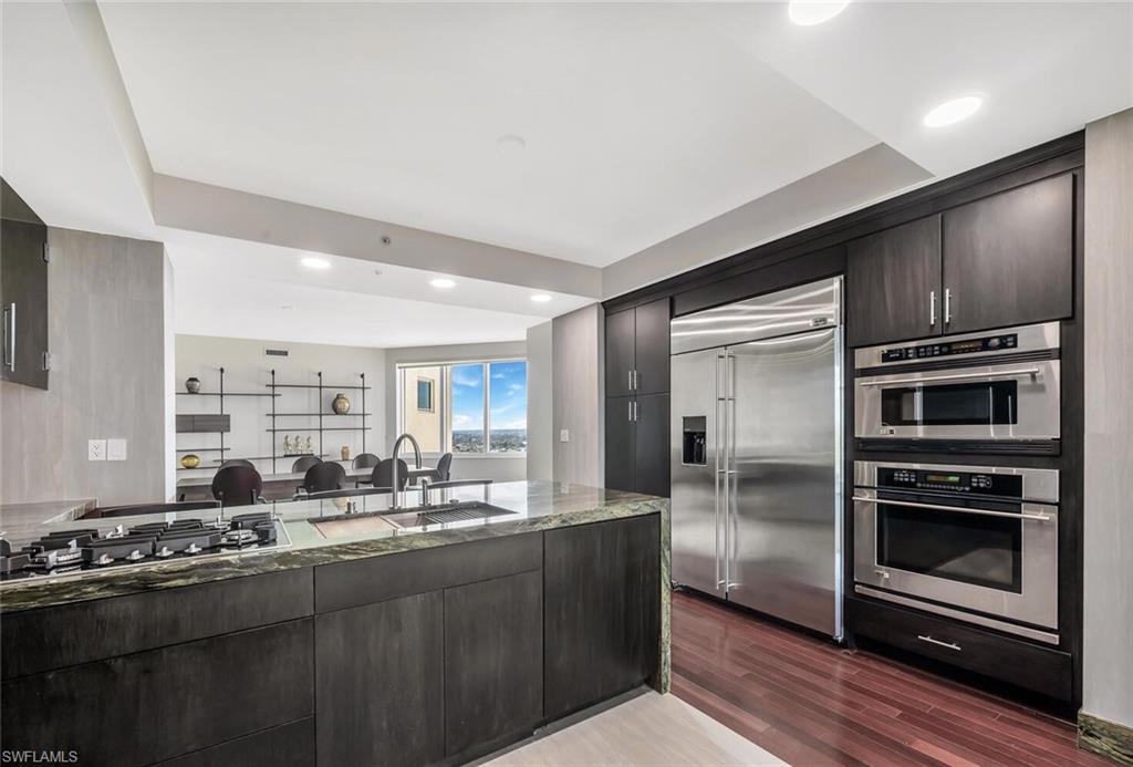 275 Indies Way, Unit 1605 Naples, FL 34110 - Photo 7 of 50 a kitchen with stainless steel appliances kitchen island granite countertop a stove a sink and a refrigerator