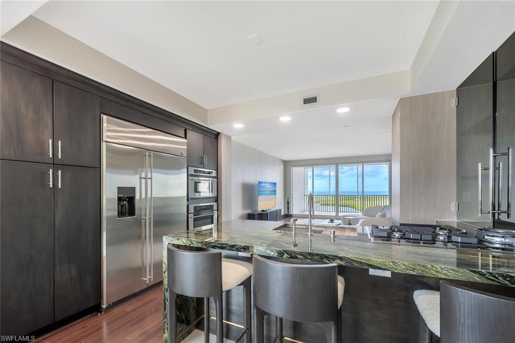275 Indies Way, Unit 1605 Naples, FL 34110 - Photo 9 of 50 a kitchen with center island table and chairs