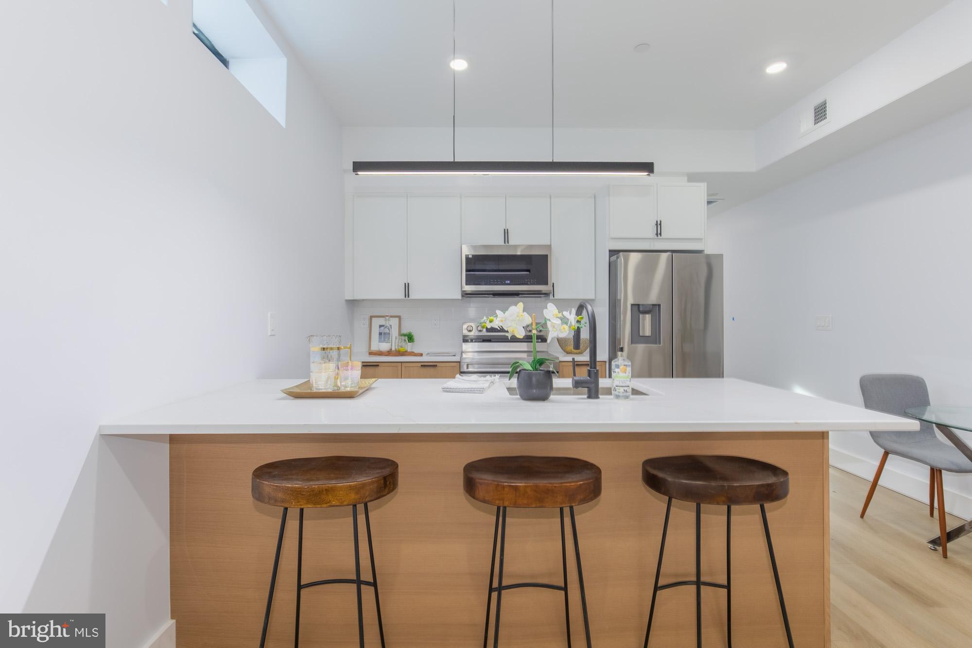 1012 17th Place Northeast, Unit 1 Washington, DC 20002 - Photo 8 of 18 a kitchen with stainless steel appliances granite countertop a dining table chairs refrigerator and cabinets