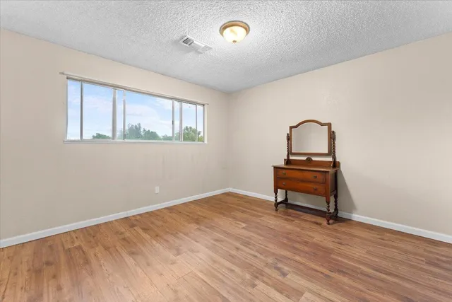 an empty room with wooden floor and natural light